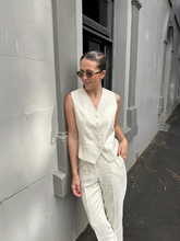 a lady wears a beige suit vest with a beige pants